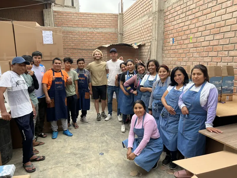 People at work in a workshop in Lima, in denim aprons, among stacked cartons